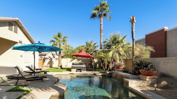 A swimming pool with lounge chairs and umbrellas, surrounded by palm trees and a clear sky. - Chandler Hideaway - Relax & Unwind | Heated pool (Chandler)