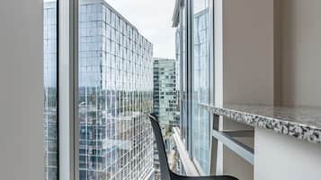 Une pièce dotée d’une grande fenêtre, d’un fauteuil noir et offrant une vue sur le paysage urbain.