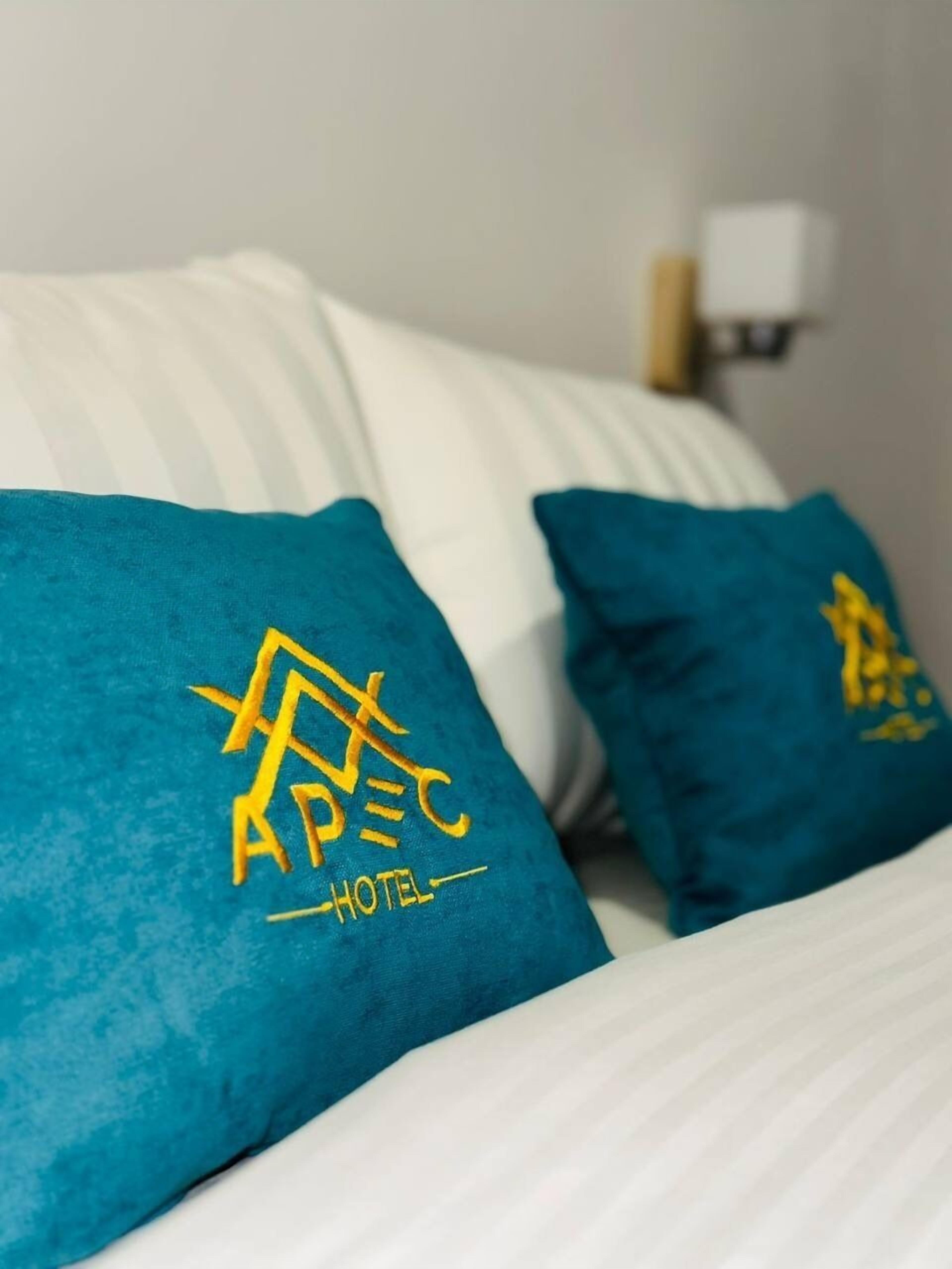 Un lit avec des oreillers de couleur turquoise ornés du logo d’un hôtel et du mot « HÔTEL ».