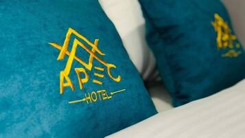 Un lit avec des oreillers de couleur turquoise ornés du logo d’un hôtel et du mot « HÔTEL ».
