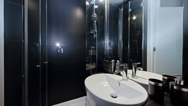 A modern bathroom with a glass-enclosed shower, a white sink, and a mirror. - Belle Epoque House of Mirror (Rome)