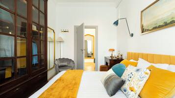 A hotel room with a large bed, a wardrobe, a desk, and a painting on the wall.