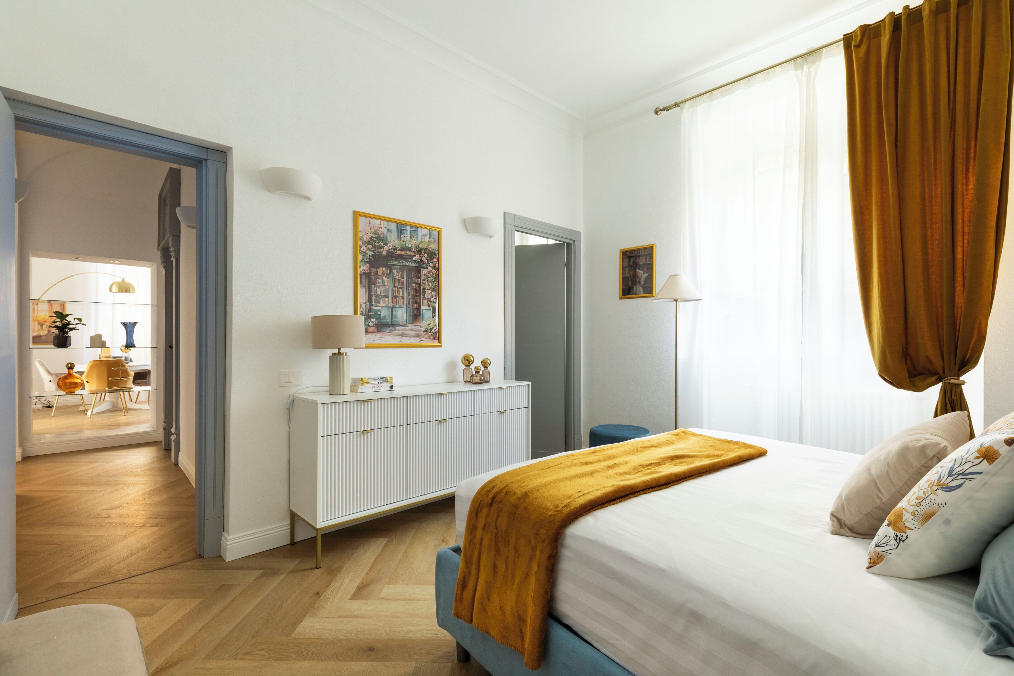 Une chambre à coucher comprenant un lit, une commode, un miroir et une porte donnant sur une salle de bain.