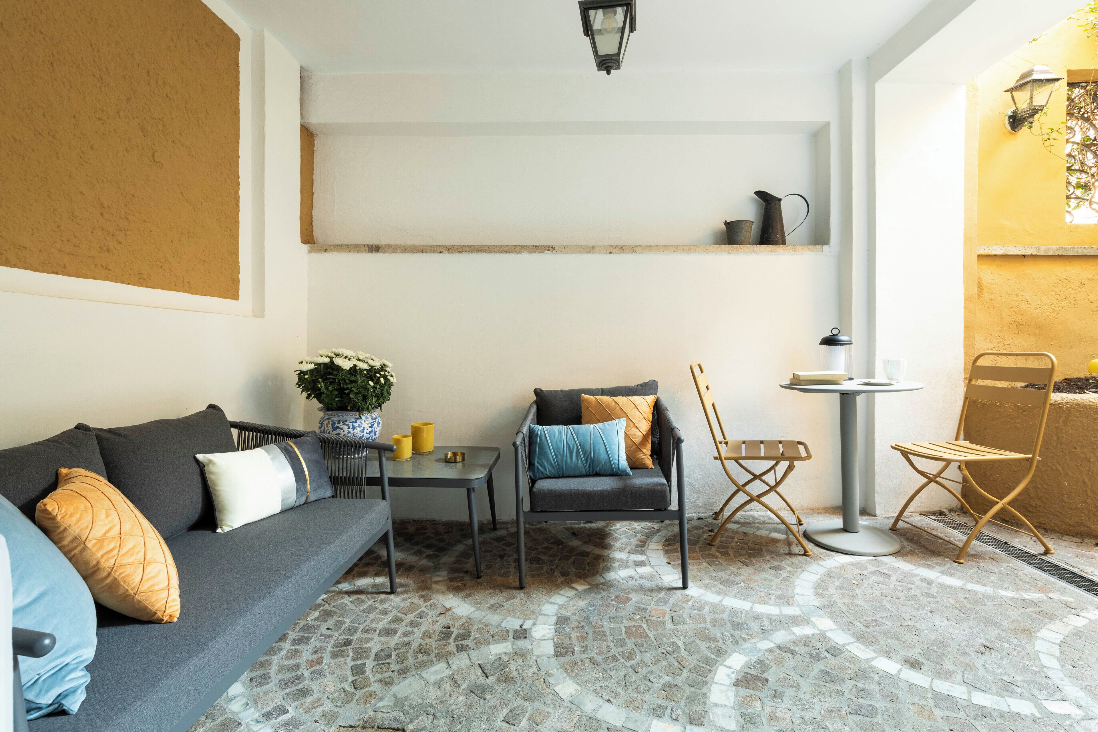 A cozy living area with a sofa, two chairs, a small table, and a potted plant.