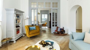 Un salon avec un canapé, une table basse et une cheminée. Au fond, on aperçoit un coin repas avec une table et des chaises.