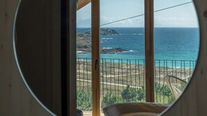 A circular window with a view of a balcony overlooking a coastal landscape. - Doniños Nature (Ferrol)