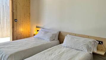 Ein Zimmer mit zwei Betten, Holzwänden und einer Decke mit freiliegenden Balken. Eine Klimaanlage ist ebenfalls vorhanden.