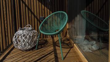 A wicker chair and a woven basket on a wooden deck.