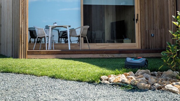 A modern two-story wooden house with a balcony, large sliding glass doors, and a patio with outdoor furniture. - Doniños Nature (Ferrol)