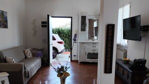 Un coin repas avec une table dressée pour deux personnes, un vase et un téléviseur fixé au mur.