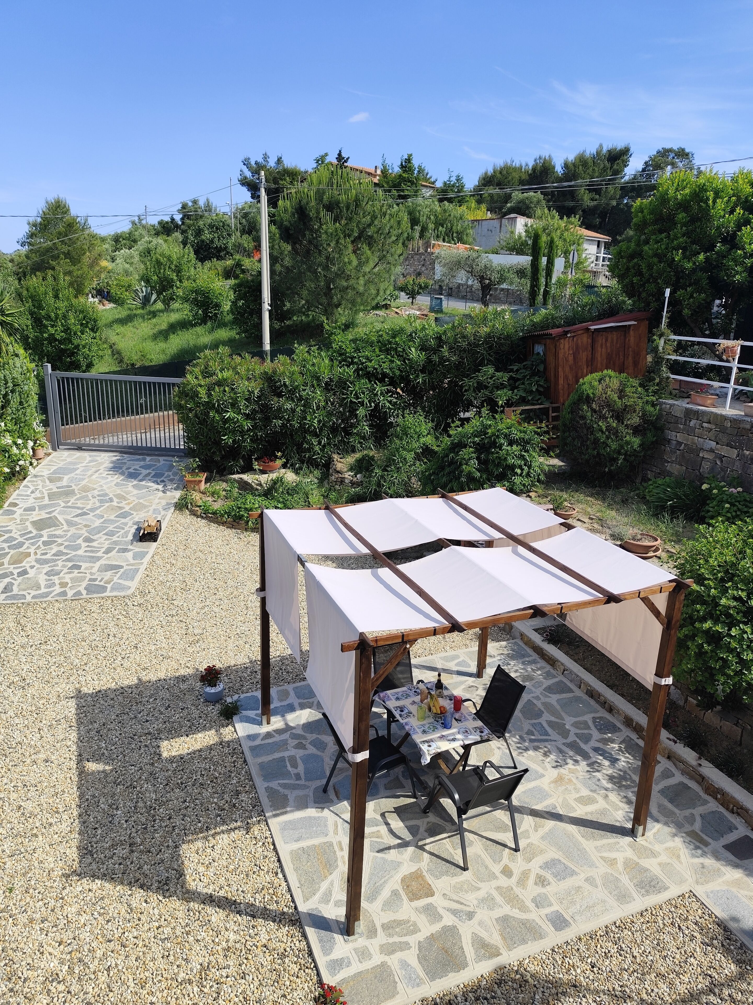 Une terrasse avec une table et des chaises, entourée d’un sol en pierre et de gravier.
