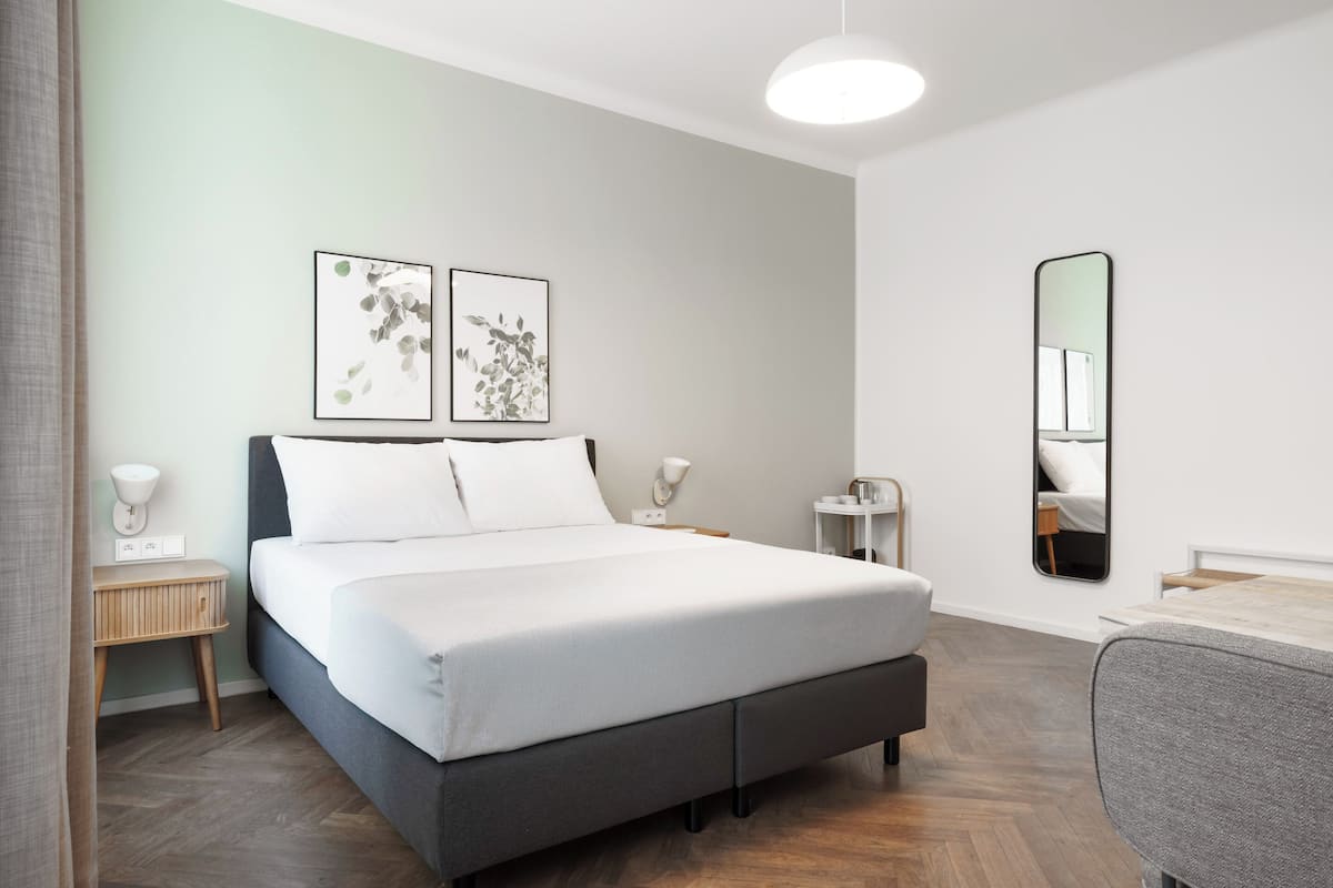 Quarto moderno com uma cama grande, mesas de cabeceira, um espelho e obras de arte na parede.