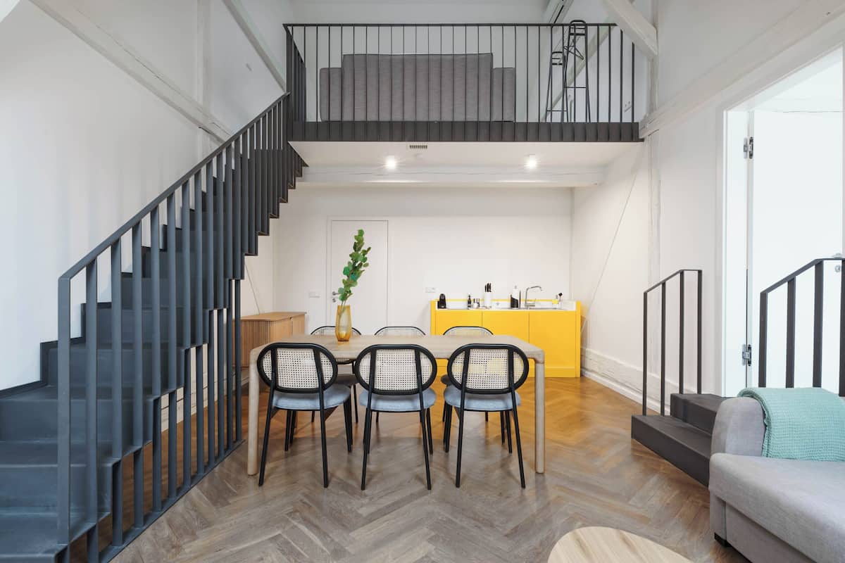 Um interior moderno com escada, área de jantar e cozinha.