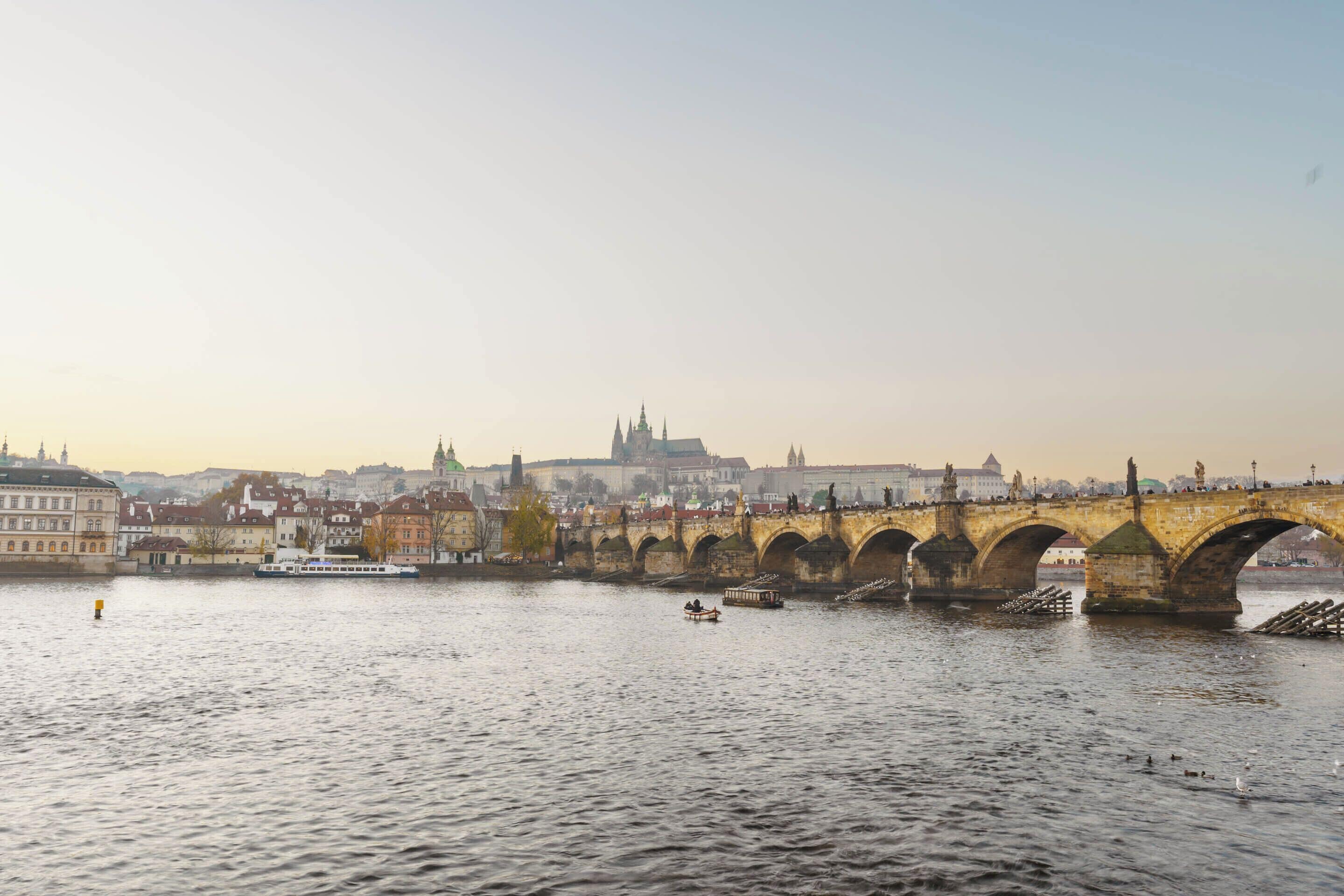 A stone bridge over a river with buildings in the background.