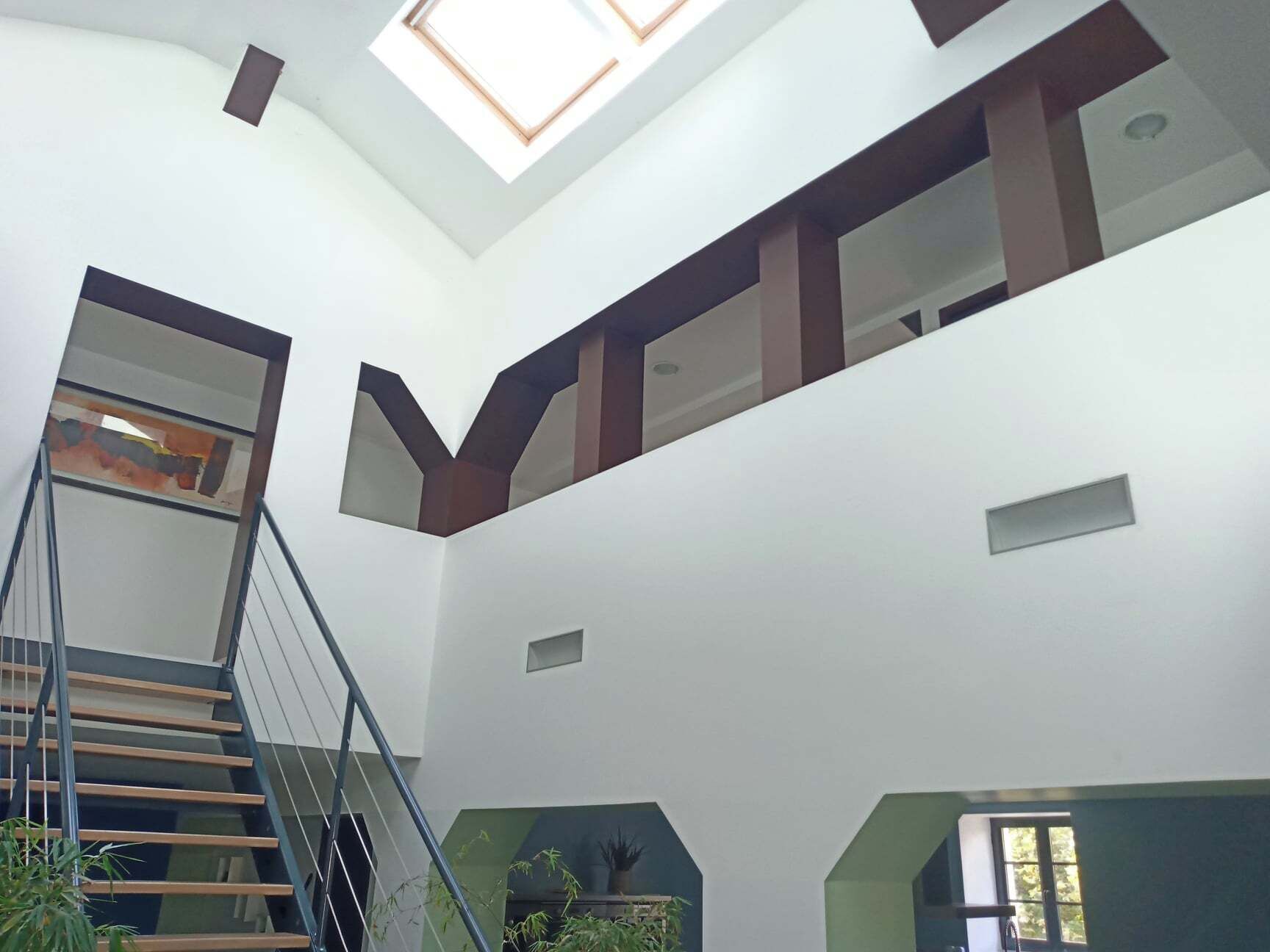 A multi-level interior with a staircase, skylights, and potted plants.