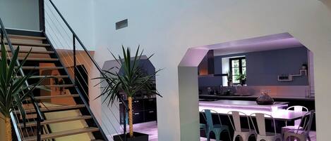 A modern interior with a staircase, a dining area, and a kitchen.