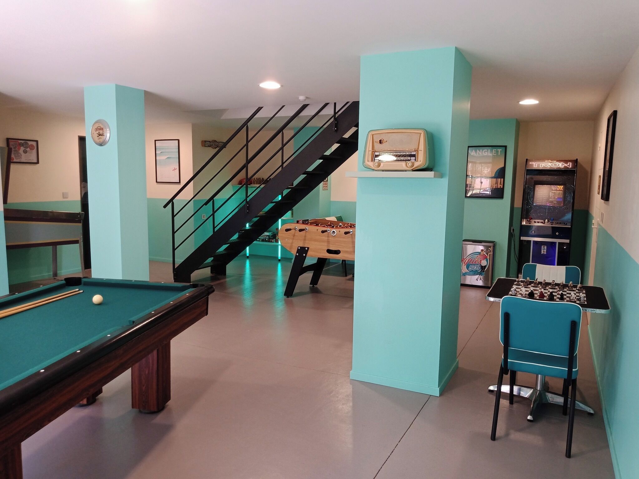 A recreational room with a pool table, foosball table, and arcade games.