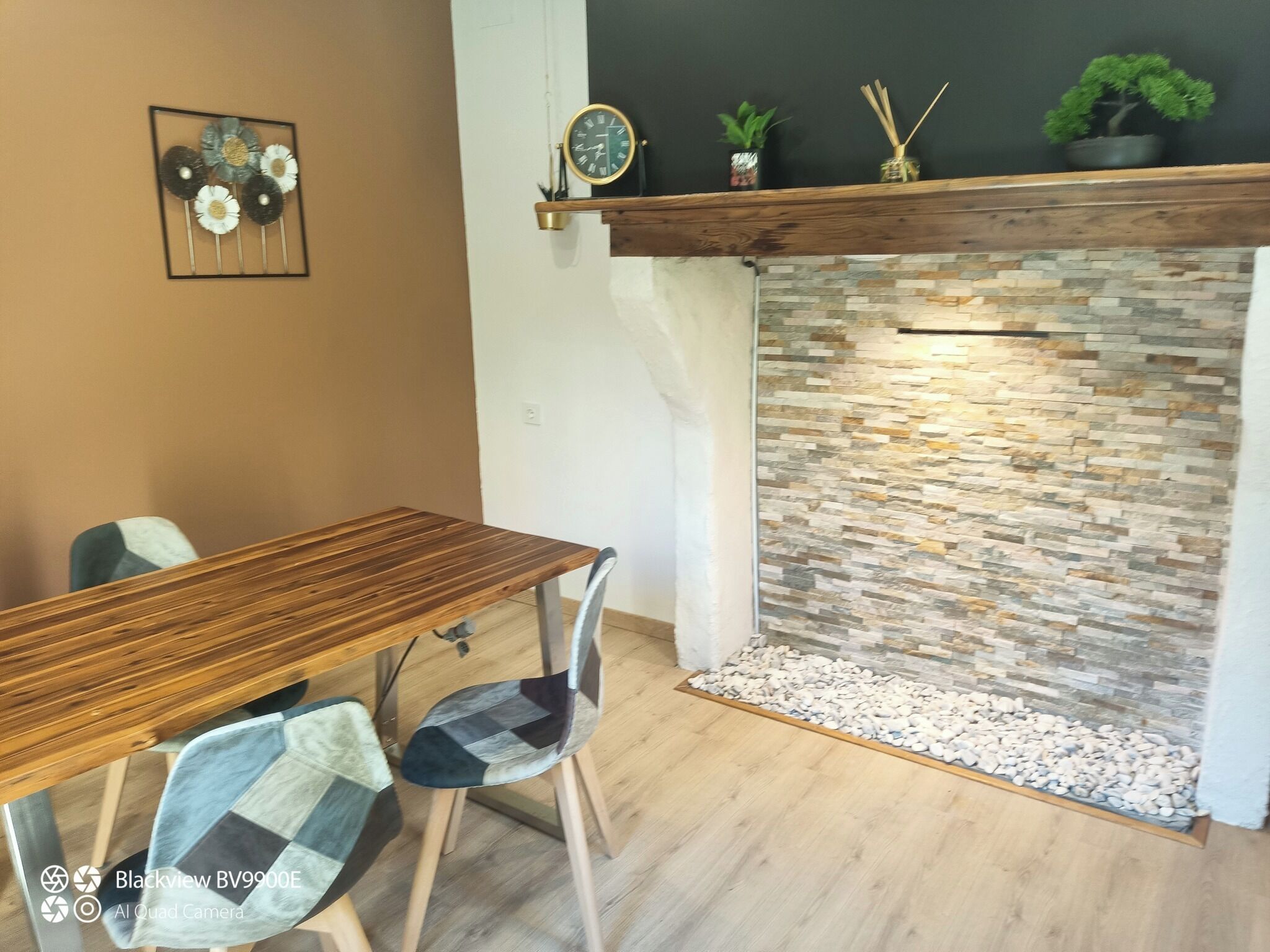 A dining area with a wooden table and chairs, a stone fireplace, and decorative wall art.