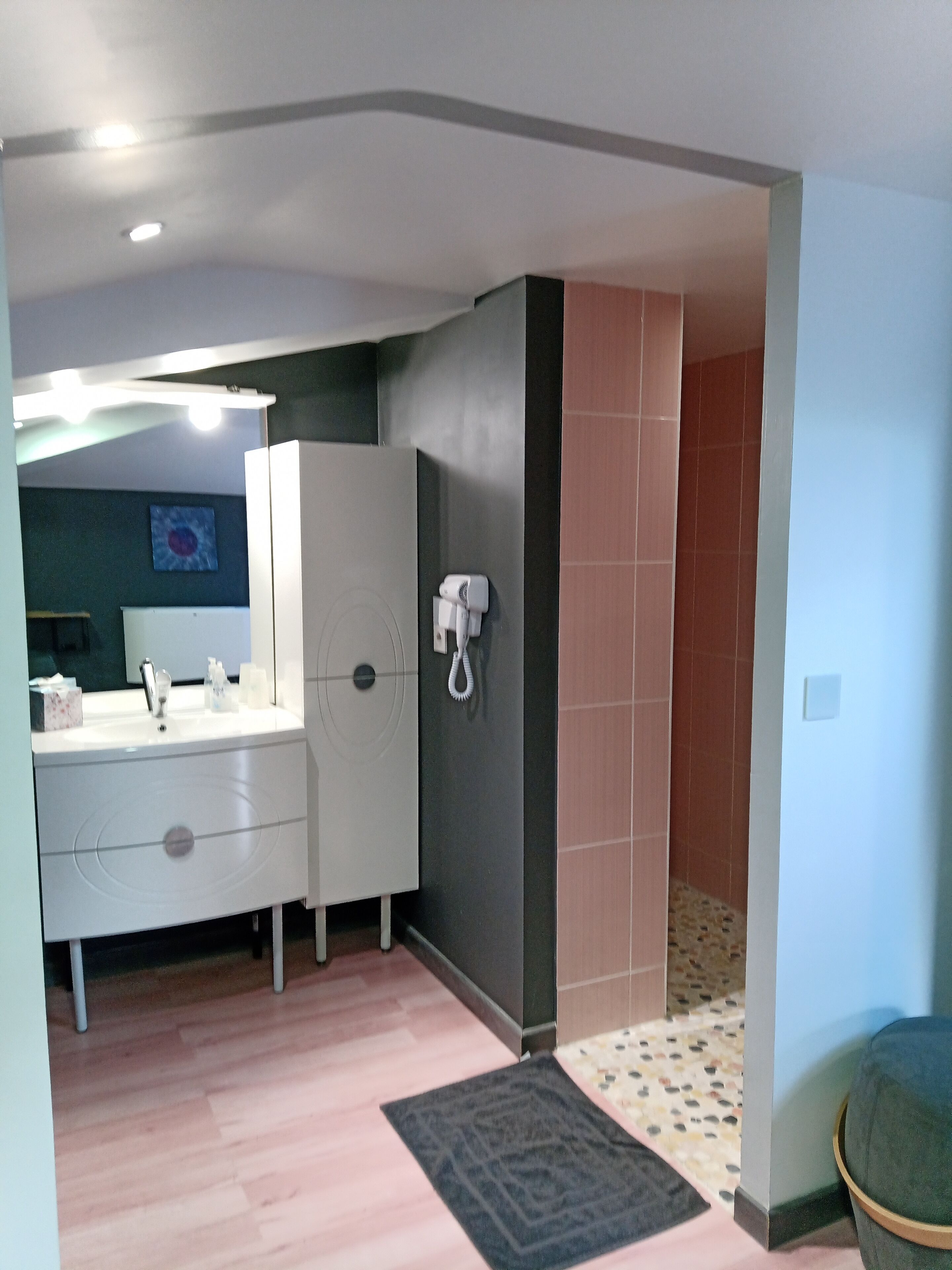 A bathroom with a white vanity, a mirror, a towel rack, and a shower area.