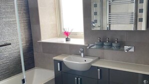 Een moderne badkamer met een bad, een wastafel, een toilet en een raam met uitzicht.