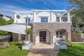 A modern villa with a stone facade, a covered patio, and a view of the interior. - Villa Serenity by MyVillaCollection (Anacapri)
