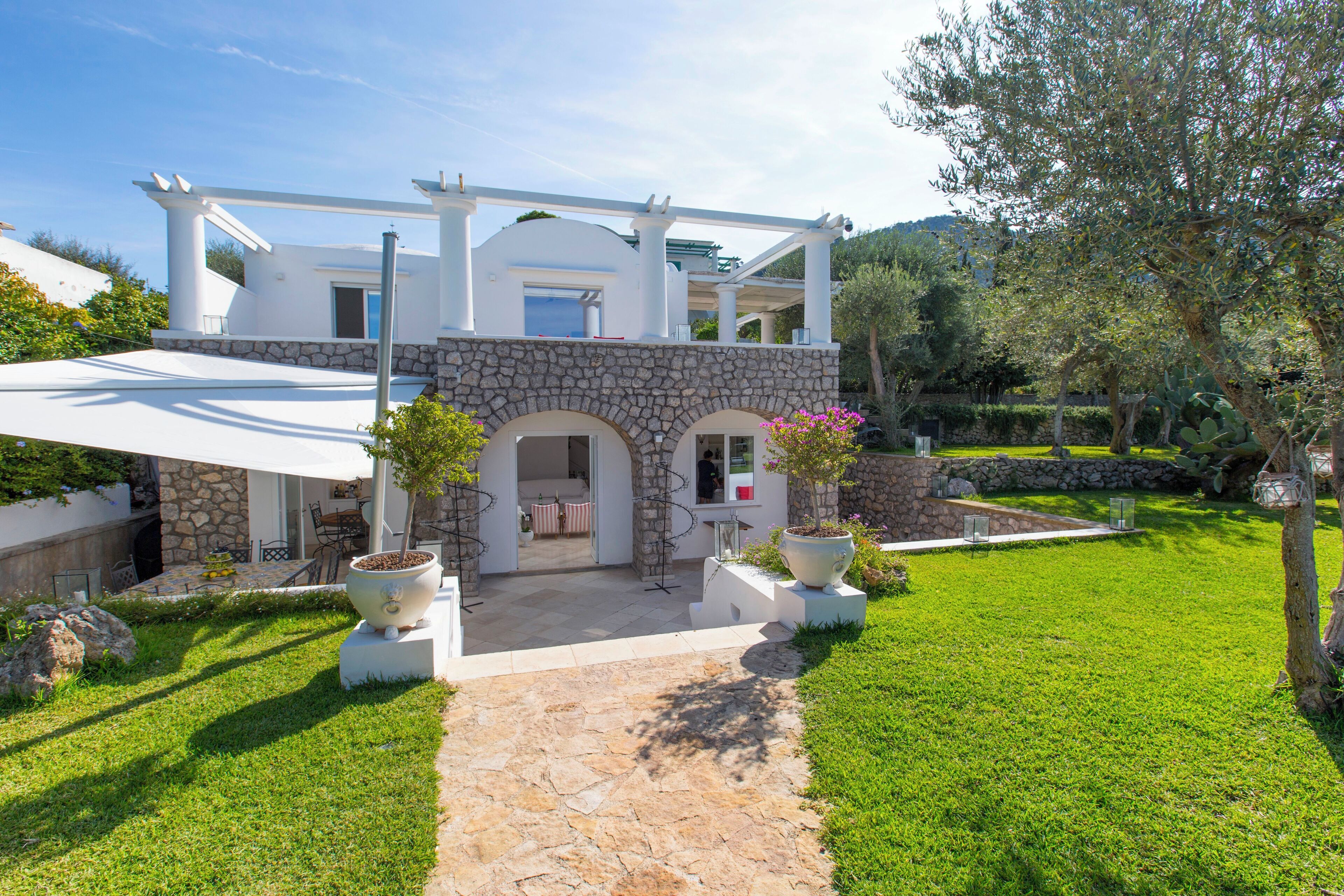 A modern house with a stone facade, a covered patio, and a well-maintained lawn.