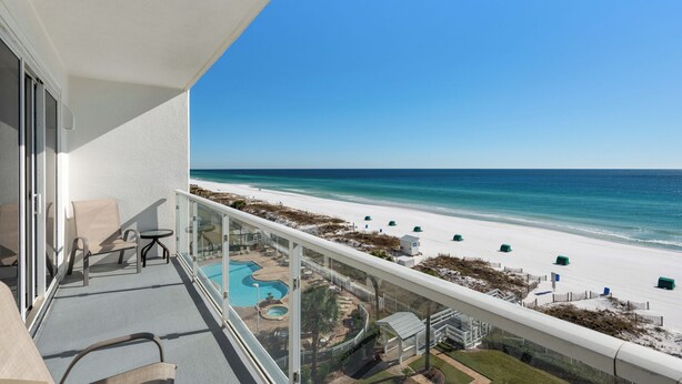 Uma varanda com vista para a praia e uma piscina.