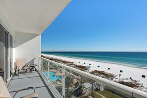 A balcony with a view of a beach and a swimming pool.