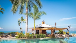 A poolside area with a gazebo, palm trees, and a view of the ocean. - Luxury room in a 5 star Hotel in Puerto Vallarta Beaches Mex. (puerto vallarta)