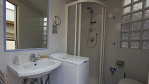 Ein Badezimmer mit Waschbecken, Spiegel, Duschkabine und Toilette.
