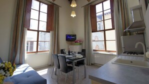 Ein gemütliches Zimmer mit Esstisch, Stühlen, Fernseher und einer Küchenzeile mit Spüle und Herd.
