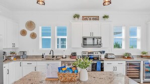 A modern kitchen with white cabinets, a granite countertop, a microwave, a toaster, and a refrigerator. - World-Class 5 Bed Villa  Oceanfront Pool/Hot tub Sunset Escape Sleeps 12 (Marathon)