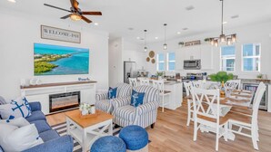 A spacious living room with a fireplace, a television, and a dining area with a kitchen in the background. - World-Class 5 Bed Villa  Oceanfront Pool/Hot tub Sunset Escape Sleeps 12 (Marathon)