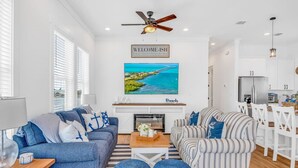 A modern living room with a fireplace, a ceiling fan, and a large TV mounted on the wall. - World-Class Oceanfront Pool/Hot tub Sunset Escape `The Lighthouse` (Marathon)