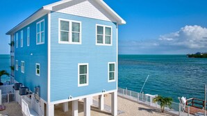 A two-story building with a white porch and a view of the ocean. - World-Class Oceanfront Pool/Hot tub Sunset Escape `The Lighthouse` (Marathon)
