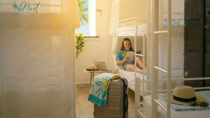 Una habitación acogedora con literas, un ordenador portátil sobre una mesita y una maleta en el suelo.