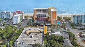 Vista aèria d'una ciutat costanera amb un hotel destacat que compta amb una piscina al terrat i vistes a la platja.