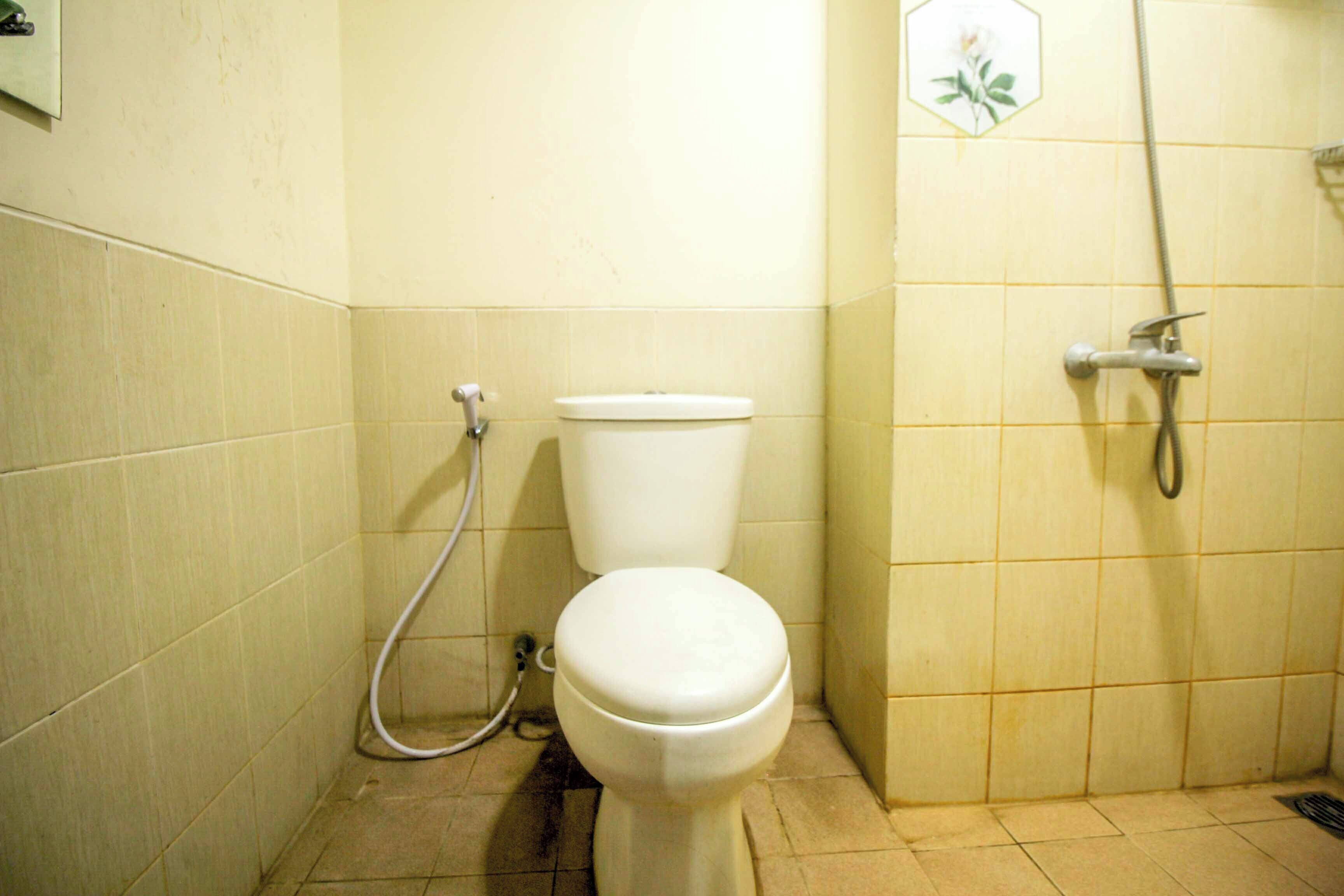 Ein kleines Badezimmer mit Toilette, Dusche und einem an der Wand befestigten Toilettenpapierhalter.