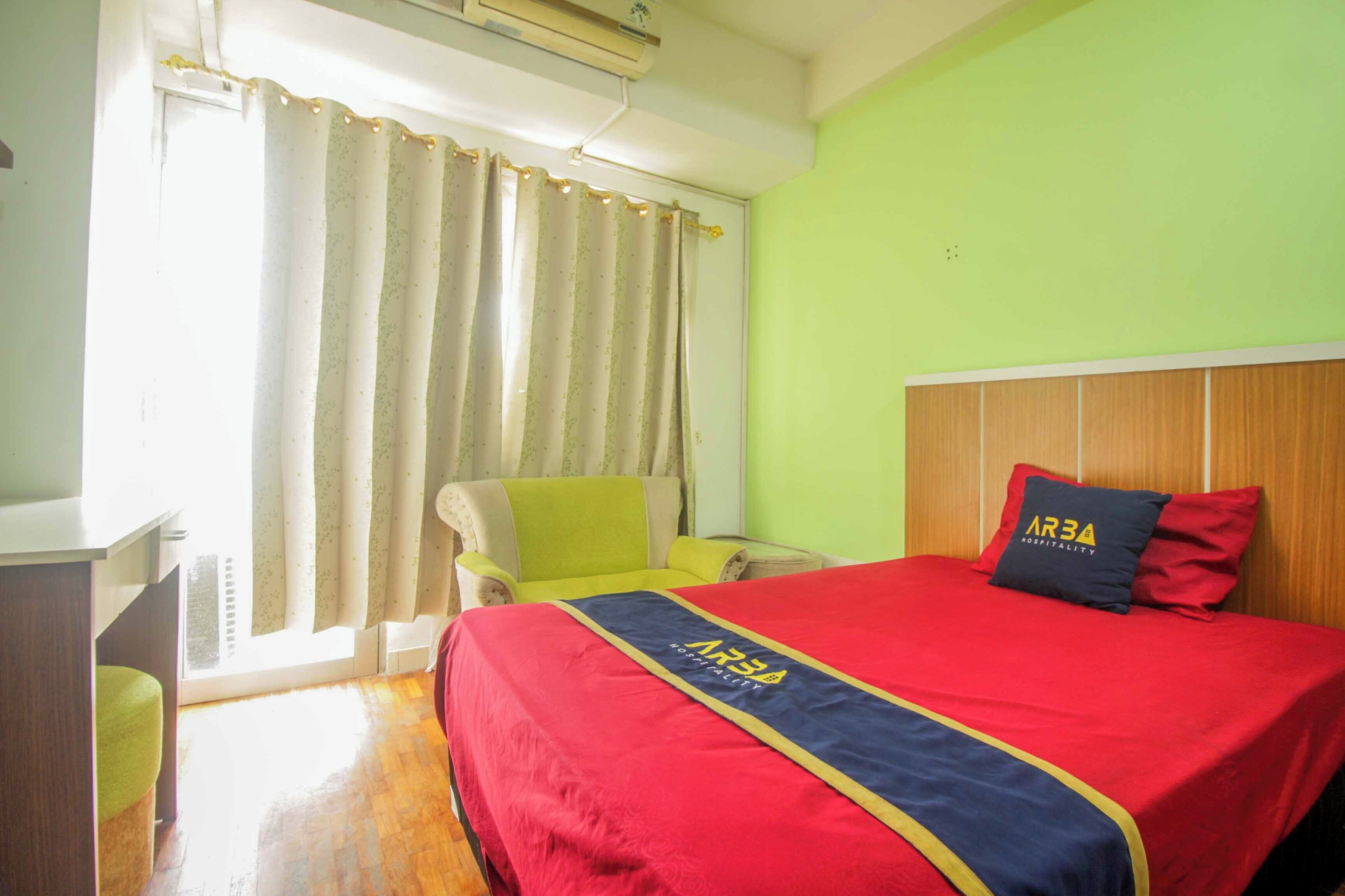 A hotel room with a bed, a desk, a chair, and a window with curtains.