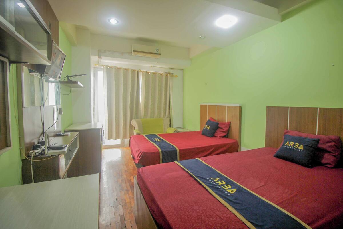Une chambre d’hôtel avec deux lits, un bureau, une chaise et un téléviseur.