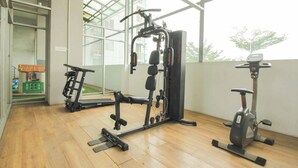 Un gimnasio con una máquina multigimnasio, una bicicleta estática y una cinta de correr.