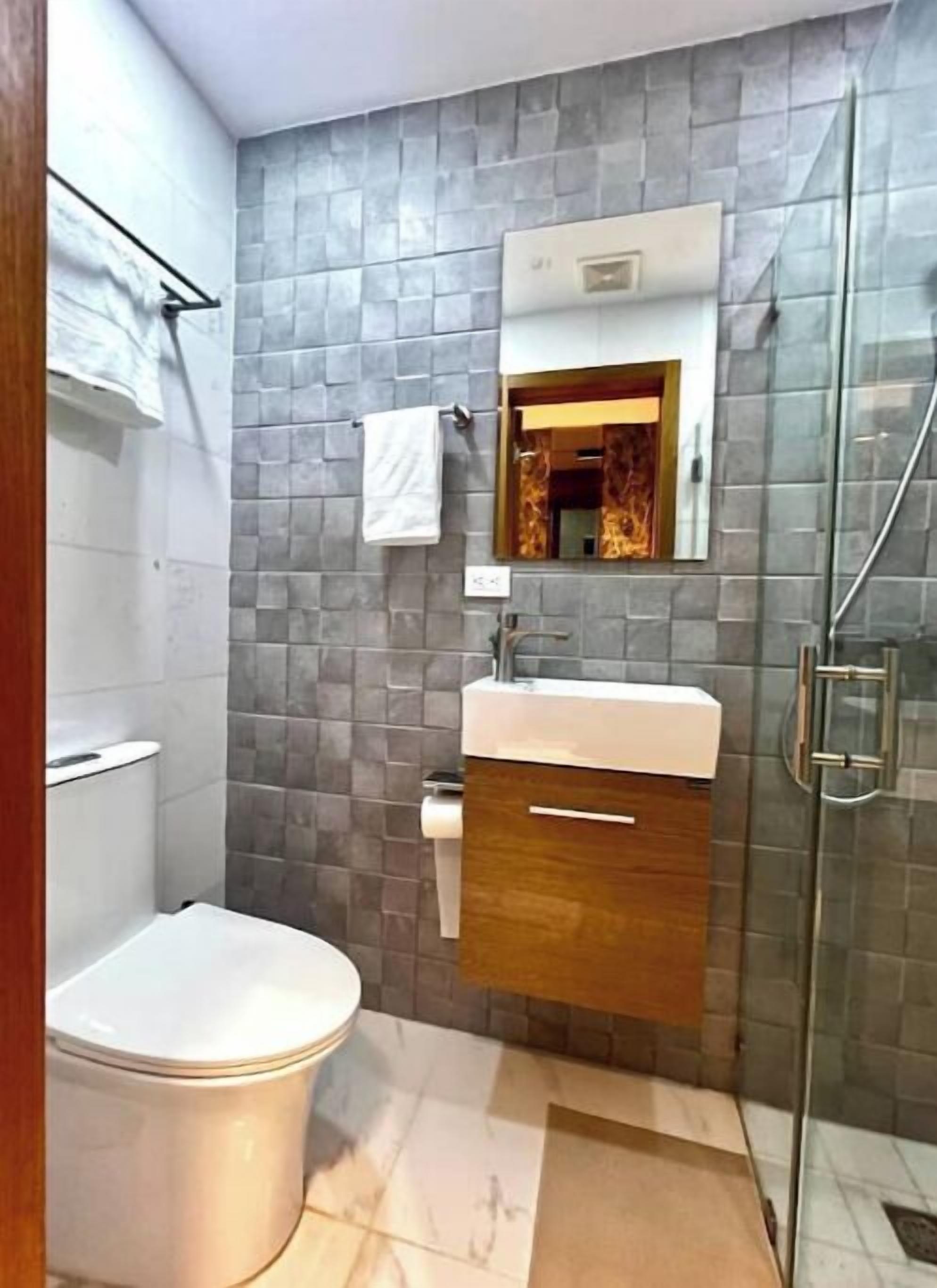 A modern bathroom with a toilet, sink, and shower.