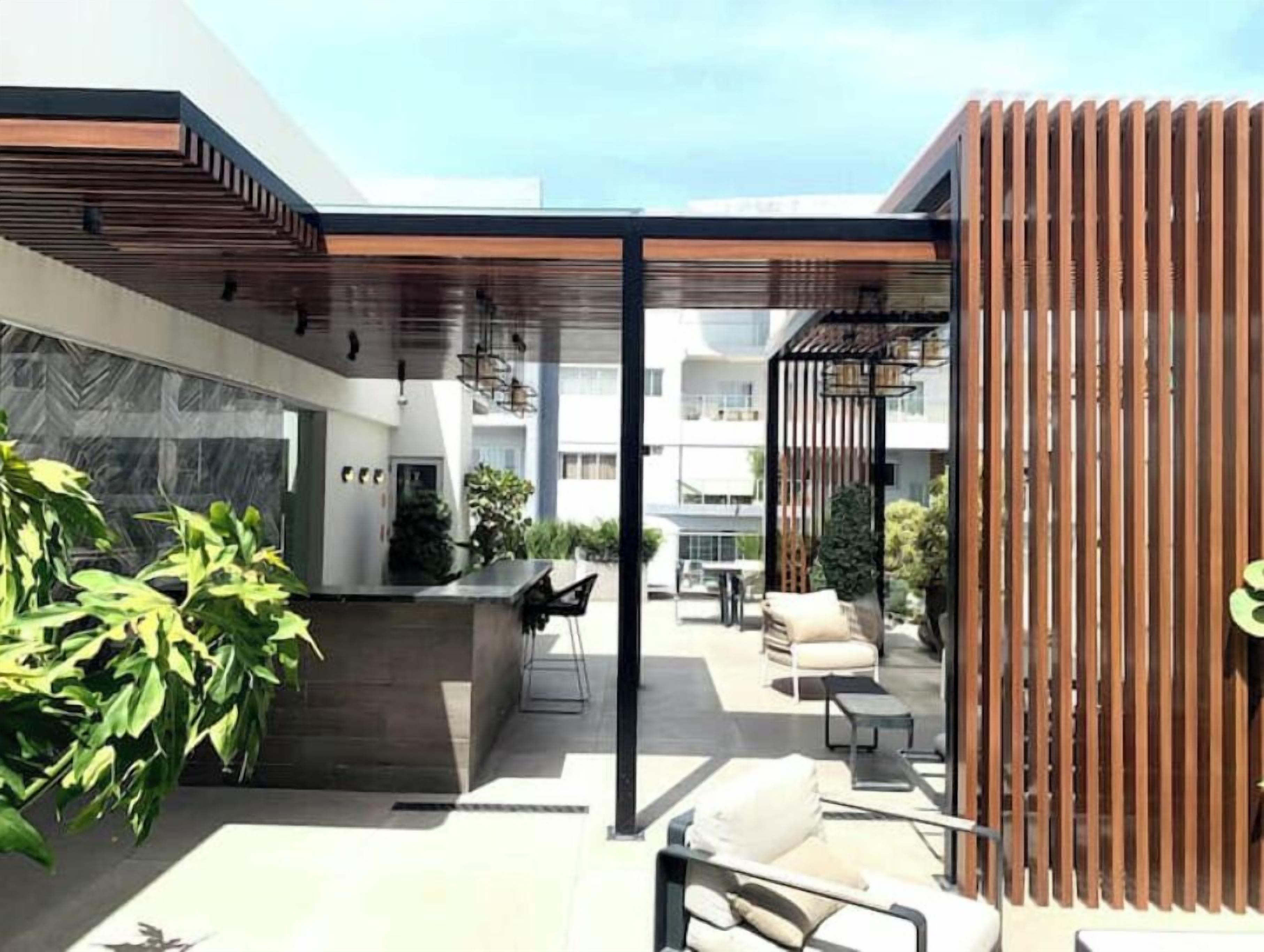 A modern outdoor area with a seating arrangement, a wooden structure, and a view of the surrounding buildings.