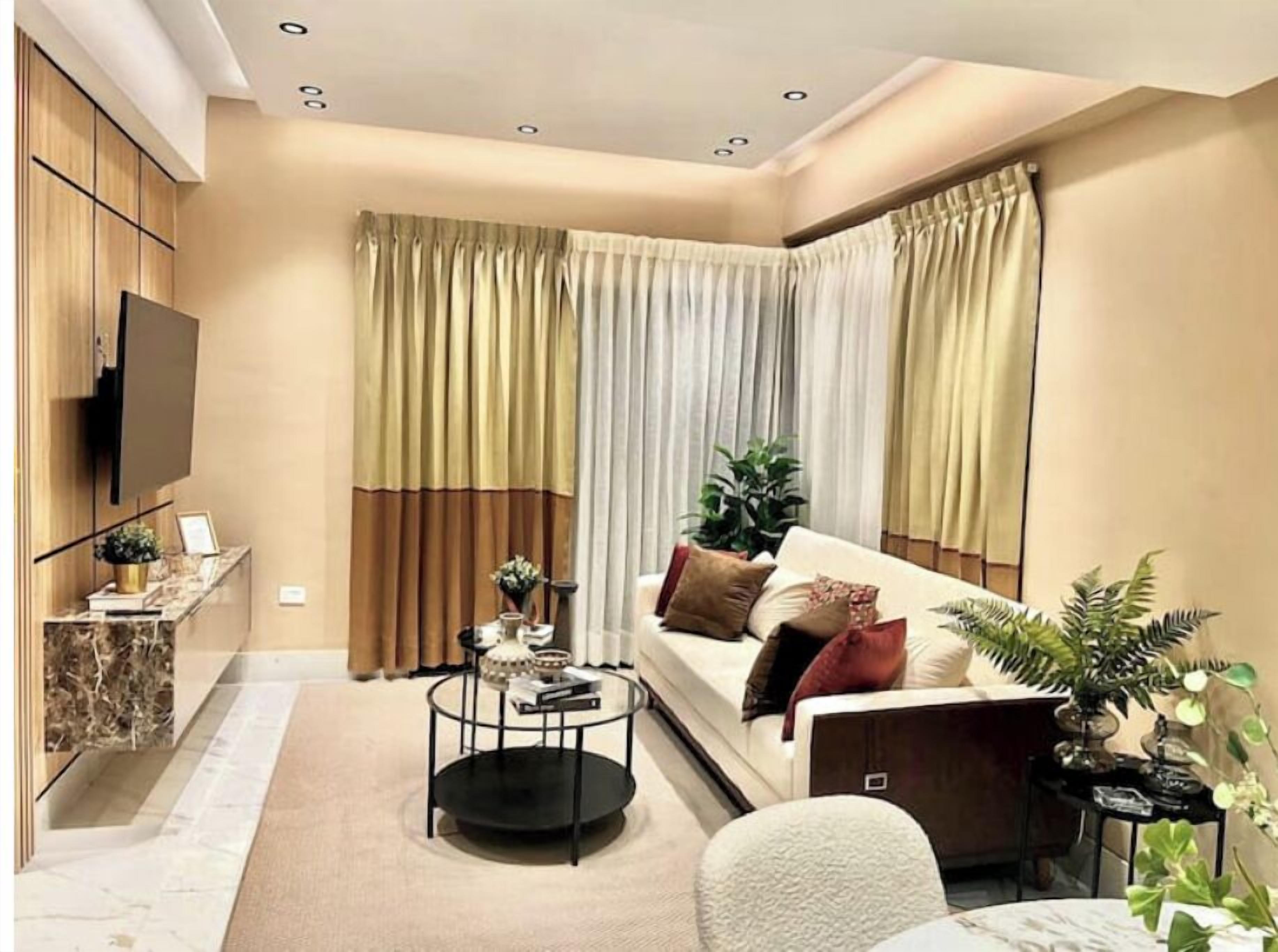 Een moderne woonkamer met een bank, een salontafel en een aan de muur bevestigde televisie.