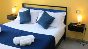 A neatly made bed with blue and white bedding, two bedside lamps, and two framed pictures on the wall. - La Ginestra - Antheia Homes (Scafati)