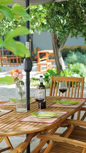 Ein Holztisch mit einer Weinflasche, einem Glas und einer Blumenvase.