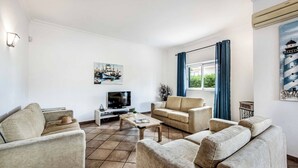 A living room with a TV, sofas, a coffee table, and a painting on the wall.