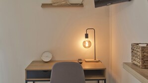 A modern workspace with a desk, chair, wall-mounted TV, and decorative items. - Pinelopi Spotless 2 BR Renovated Apt Athens Center (Athens)