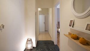 A hallway with a marble floor, a wall-mounted mirror, and a shelf with pumpkins. - Pinelopi Spotless 2 BR Renovated Apt Athens Center (Athens)
