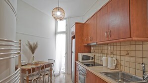 A modern kitchen with wooden cabinets, a microwave, an oven, and a sink. - Pinelopi Spotless 2 BR Renovated Apt Athens Center (Athens)